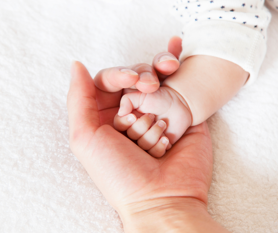 Parents hand holding new baby's hand