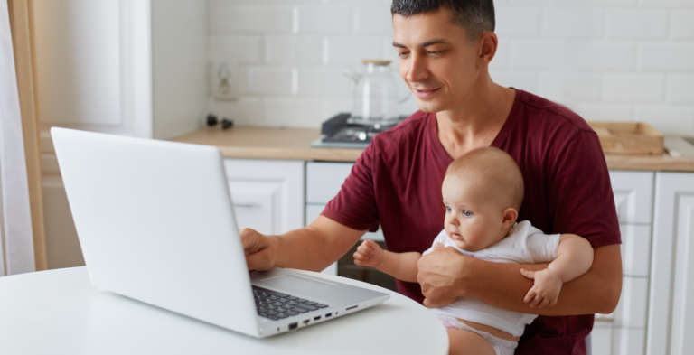Dad holding child while looking at computer