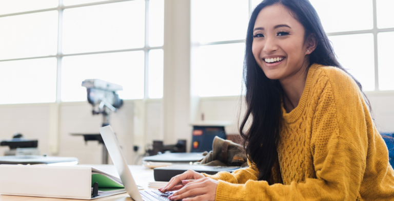 Student in yellow sweater on computer looking at student loan payments