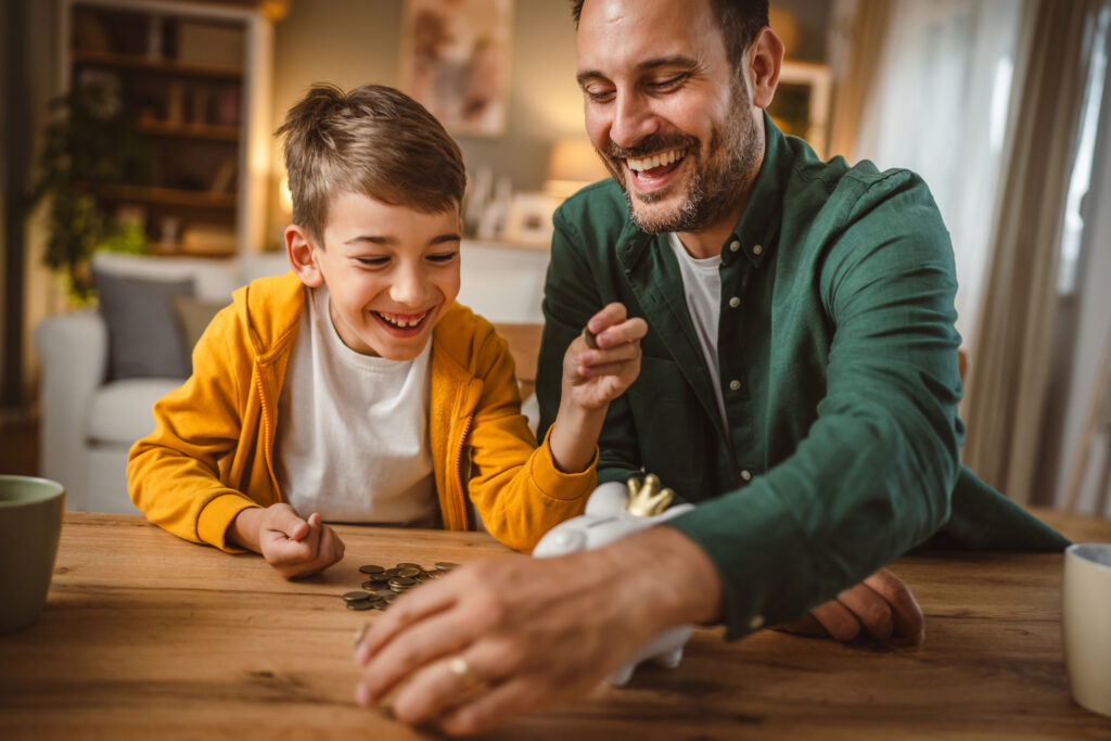 Father and son save money coins together at piggy bank at home