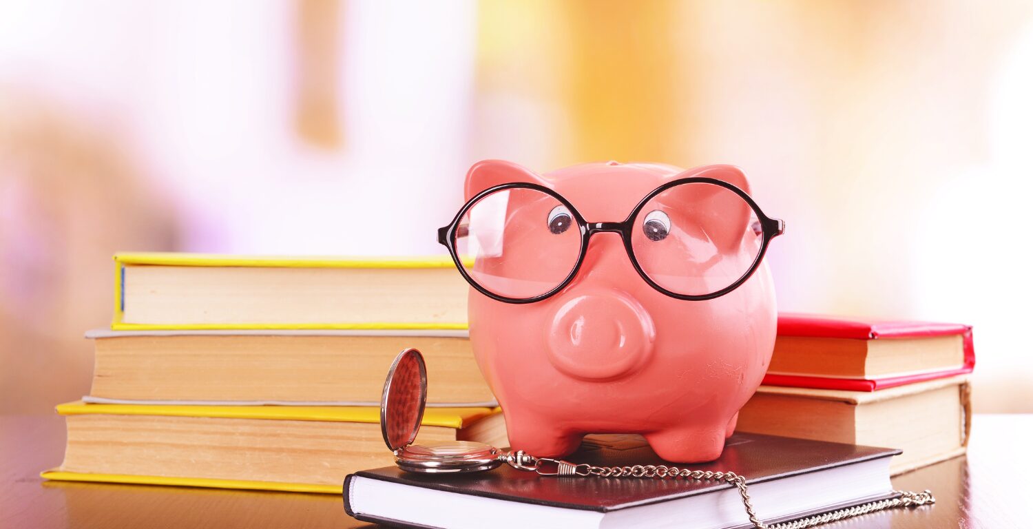 piggy bank wearing glasses sitting on finance books