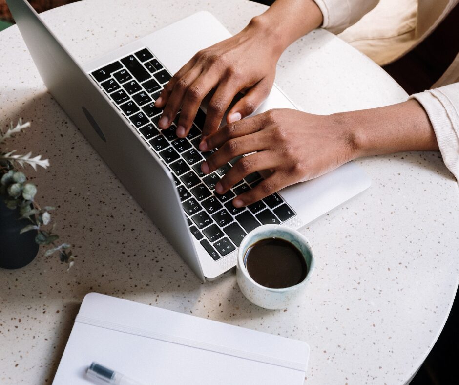 Person typing on laptop with coffee nearby