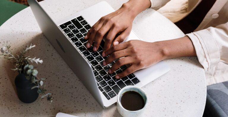 Person typing on laptop with coffee nearby